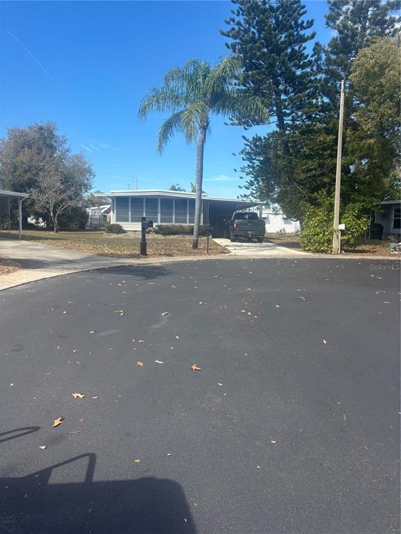 A single-story house with a carport and a palm tree sits along a paved street — 105 FREEDOM COURT UNIT 30, PALM HARBOR, FL