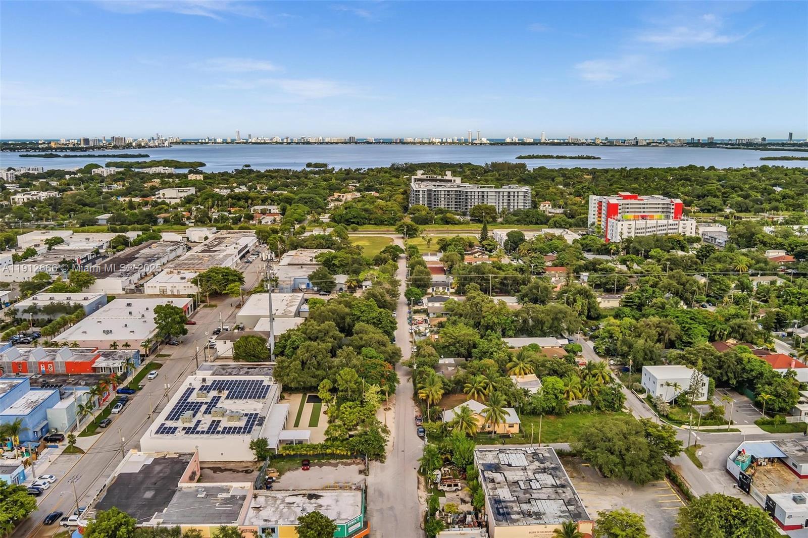 A white single-story house with a black-trimmed exterior sits behind a black metal fence — 5850 NE 3rd Ave, Miami FL 33137, MIAMI, FL