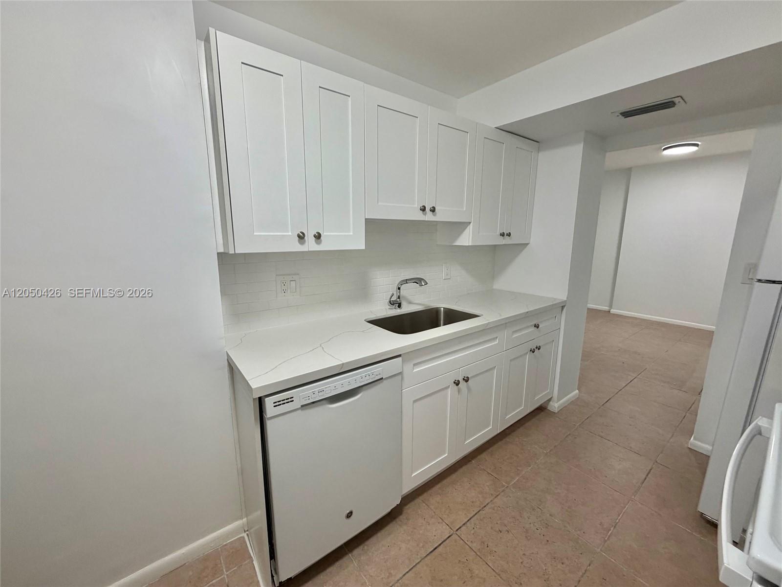 A kitchen features white cabinets, a white dishwasher, a stainless steel sink, and stone countertops — 4400 Hillcrest Dr # 308A, Hollywood FL 33021, HOLLYWOOD, FL