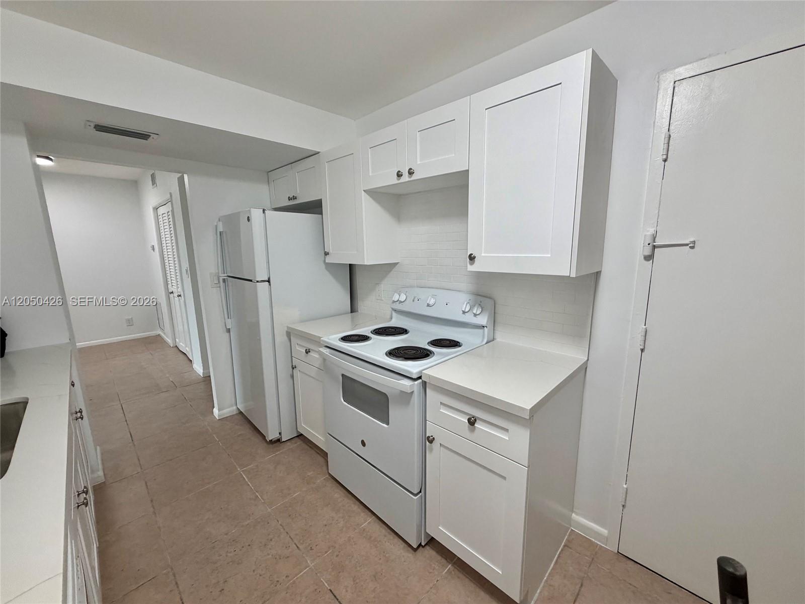 A kitchen features white cabinets, white appliances, and light-colored countertops over tiled floors — 4400 Hillcrest Dr # 308A, Hollywood FL 33021, HOLLYWOOD, FL