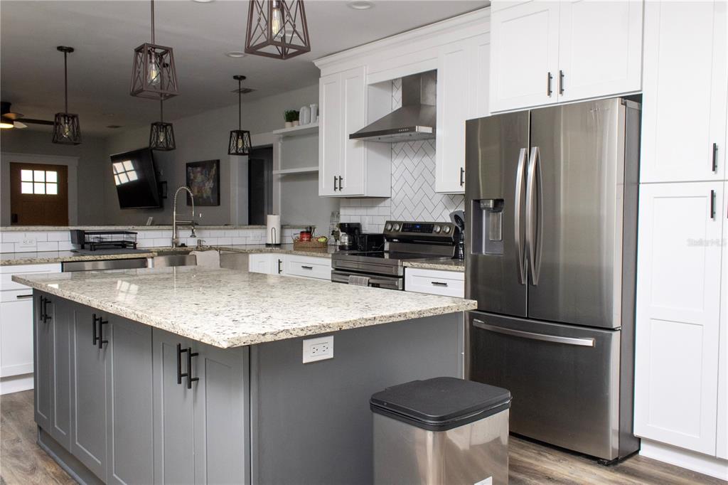 A kitchen features a gray island with granite countertops, white cabinetry, and stainless steel appliances — 2910 N OLA AVENUE, TAMPA, FL