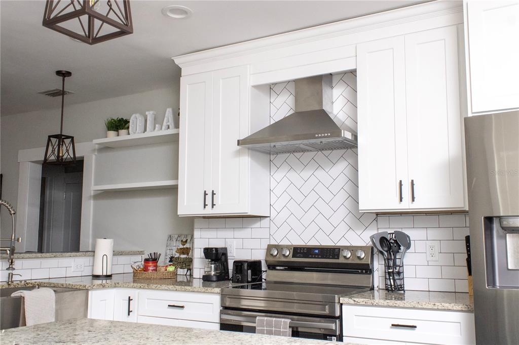 A kitchen features white cabinets, stainless steel appliances, and a herringbone-patterned tile backsplash — 2910 N OLA AVENUE, TAMPA, FL