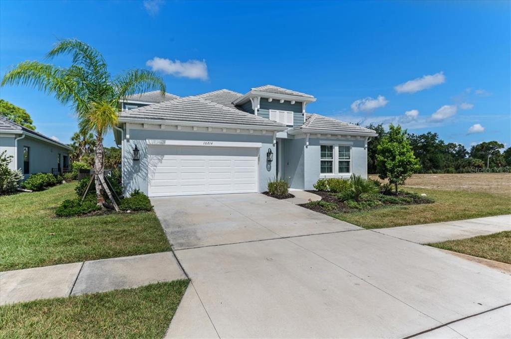 A light blue single-story house with a two-car garage and a concrete driveway — 10214 CRYSTAL ISLES CIRCLE, SARASOTA, FL
