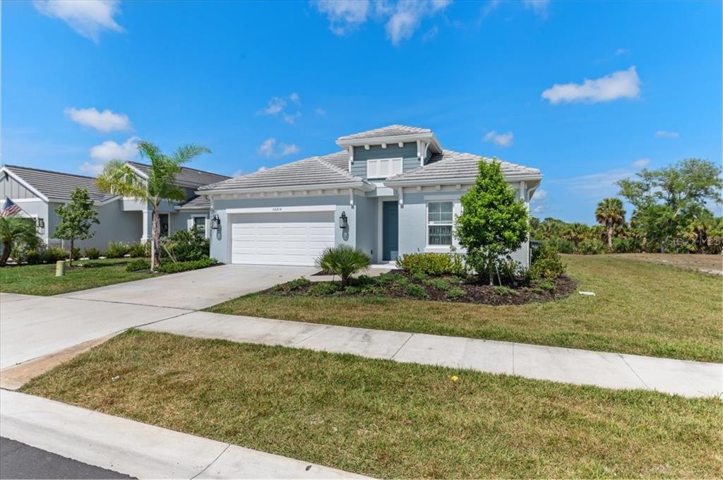 A light blue single-story house with a two-car garage and a tiled roof — 10214 CRYSTAL ISLES CIRCLE, SARASOTA, FL