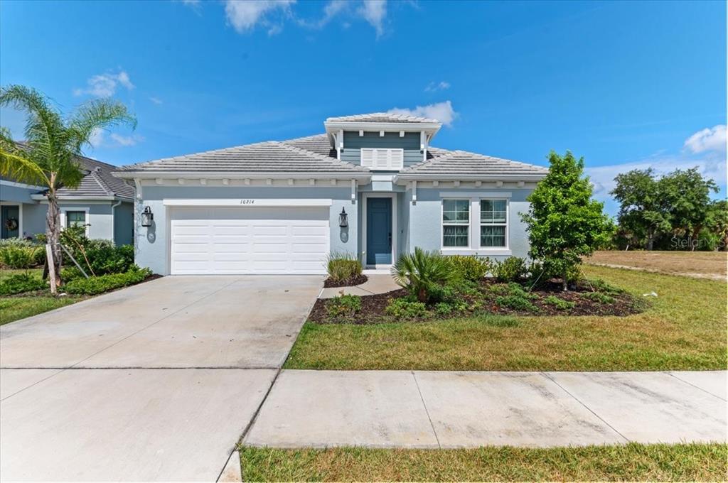A light blue single-story house features a two-car garage, a front entrance, and landscaping — 10214 CRYSTAL ISLES CIRCLE, SARASOTA, FL