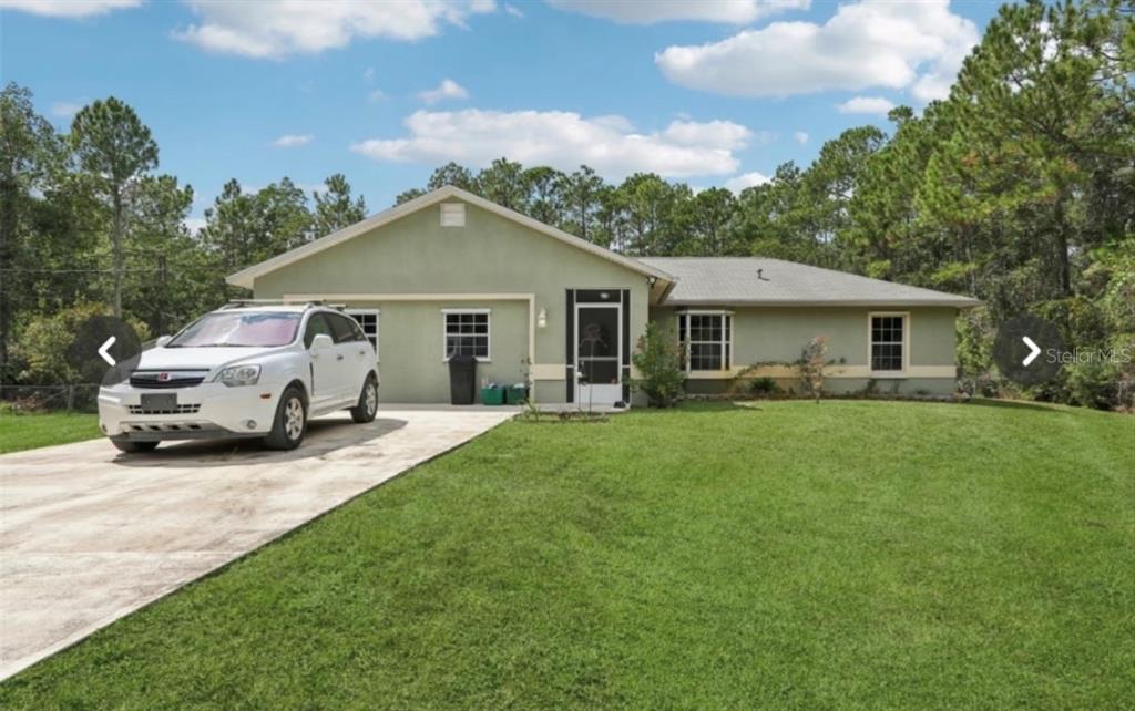 A single-story house with a light green exterior, a concrete driveway, and a white car — 1594 PAPAYA STREET, BUNNELL, FL