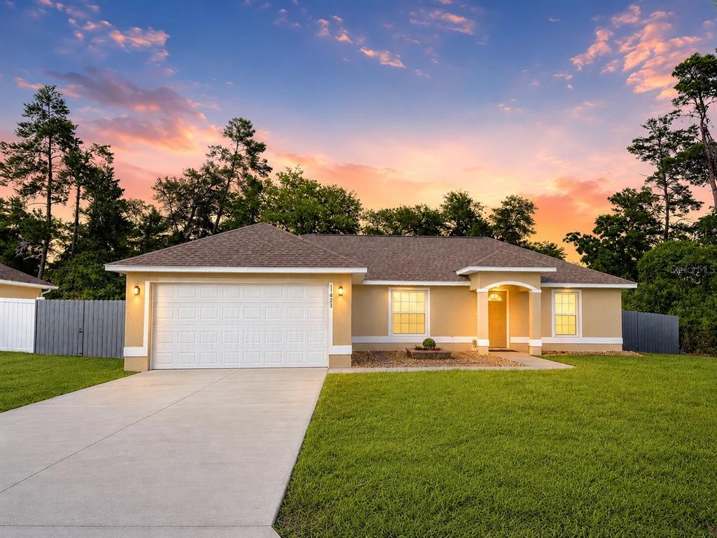 A single-story house with a two-car garage and a concrete driveway at sunset — 17023 SW 41ST AVENUE, OCALA, FL