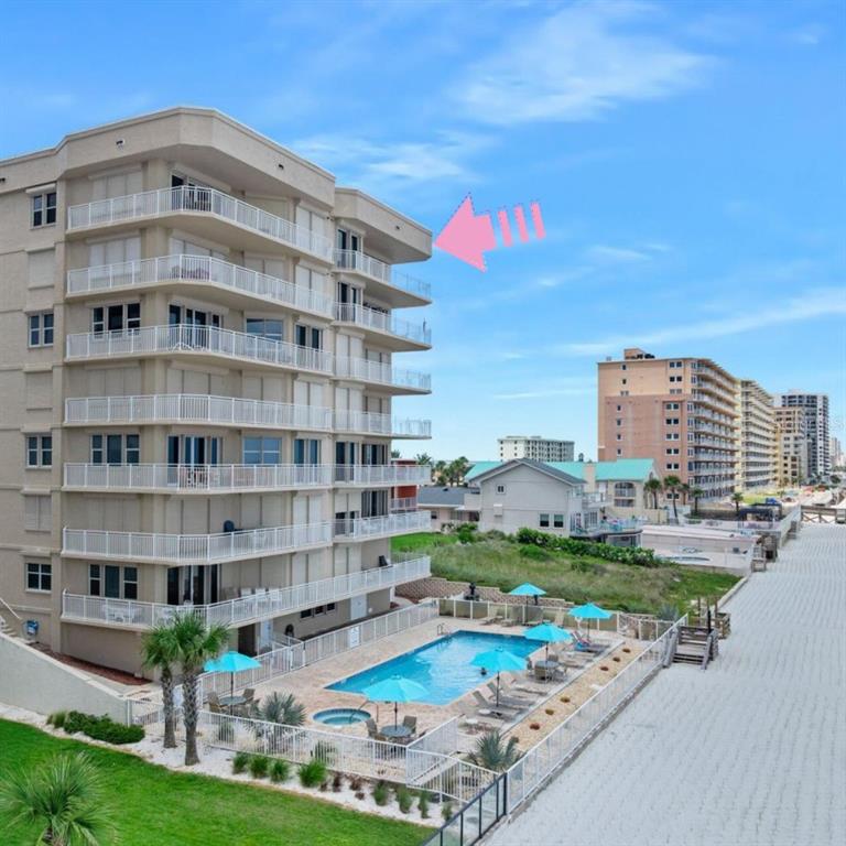 An aerial view shows a beach with a tall residential building and a smaller condo complex — 3851 S ATLANTIC AVENUE UNIT 701, DAYTONA BEACH, FL