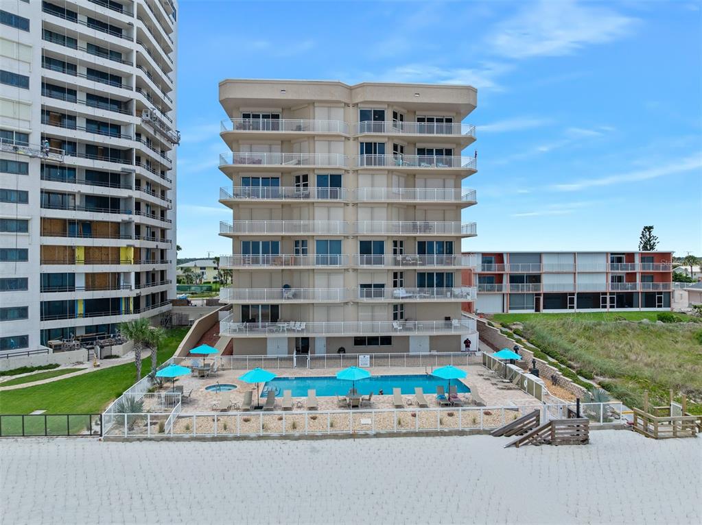 An exterior view of a multi-story beachfront condominium building with a swimming pool — 3851 S ATLANTIC AVENUE UNIT 701, DAYTONA BEACH, FL