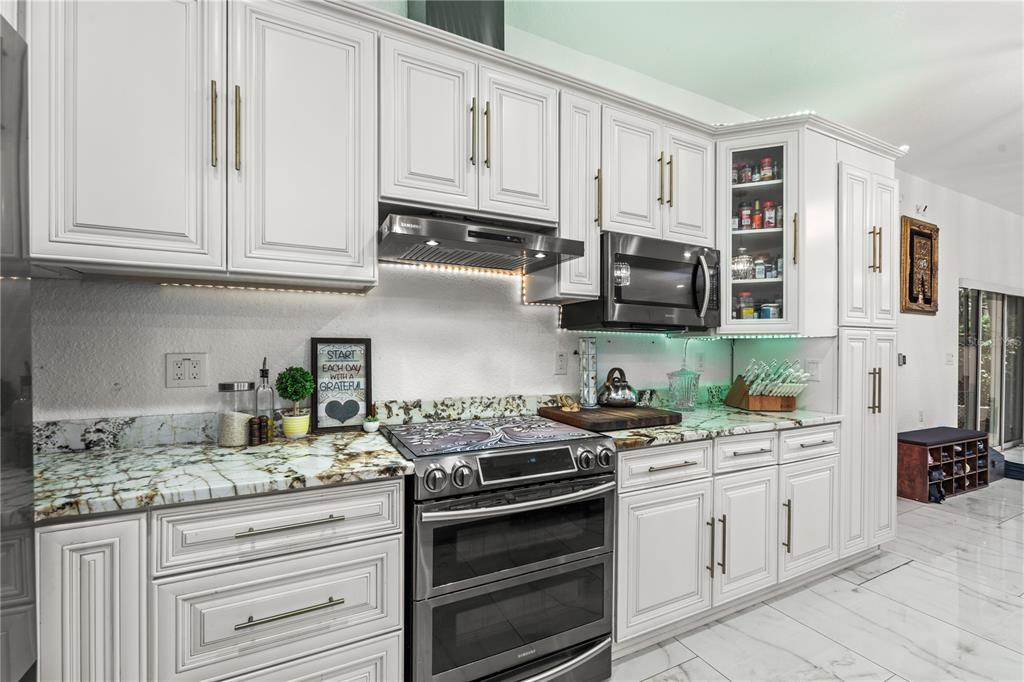 A kitchen features white cabinetry, stainless steel appliances, and patterned stone countertops — 2520 GOMAZ WAY S, ST PETERSBURG, FL