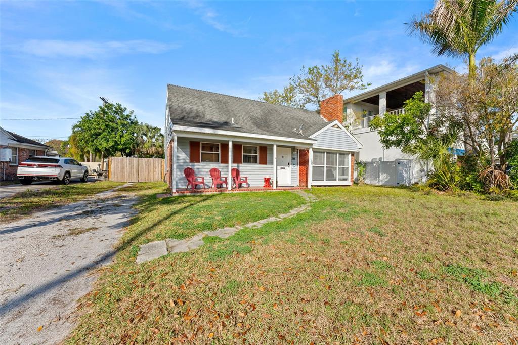 A single-story house with gray siding, a brick chimney, and a front porch with chairs — 544 SEVERN AVENUE, TAMPA, FL