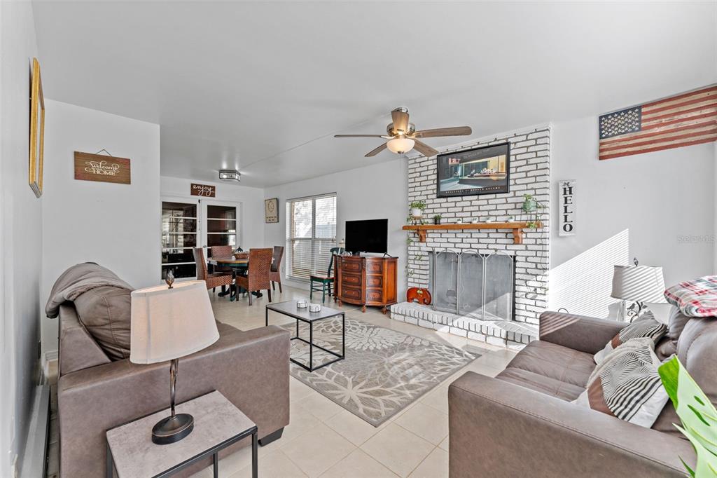 A living room features a white brick fireplace, tile flooring, and an adjacent dining area — 544 SEVERN AVENUE, TAMPA, FL