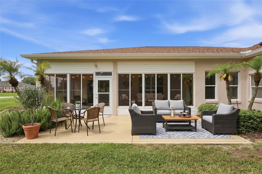 A patio with outdoor furniture sits in front of a house with a screened-in porch — 5036 SAWGRASS LAKE CIRCLE, LEESBURG, FL
