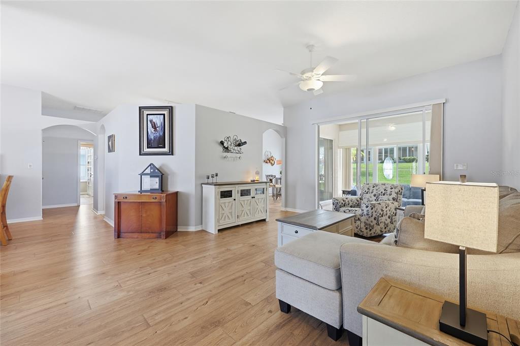 A living room features light wood flooring, a ceiling fan, and sliding glass doors — 5036 SAWGRASS LAKE CIRCLE, LEESBURG, FL