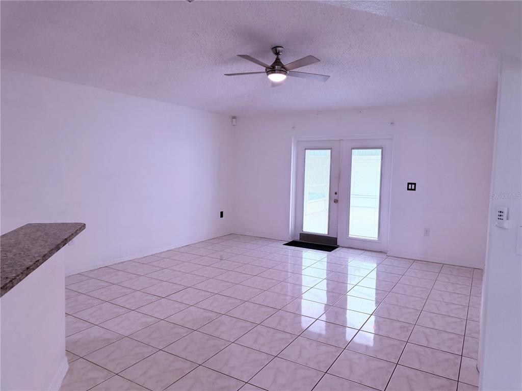 A room with white walls, tile flooring, a ceiling fan, and glass double doors — 161 CHINA BERRY CIRCLE, DAVENPORT, FL