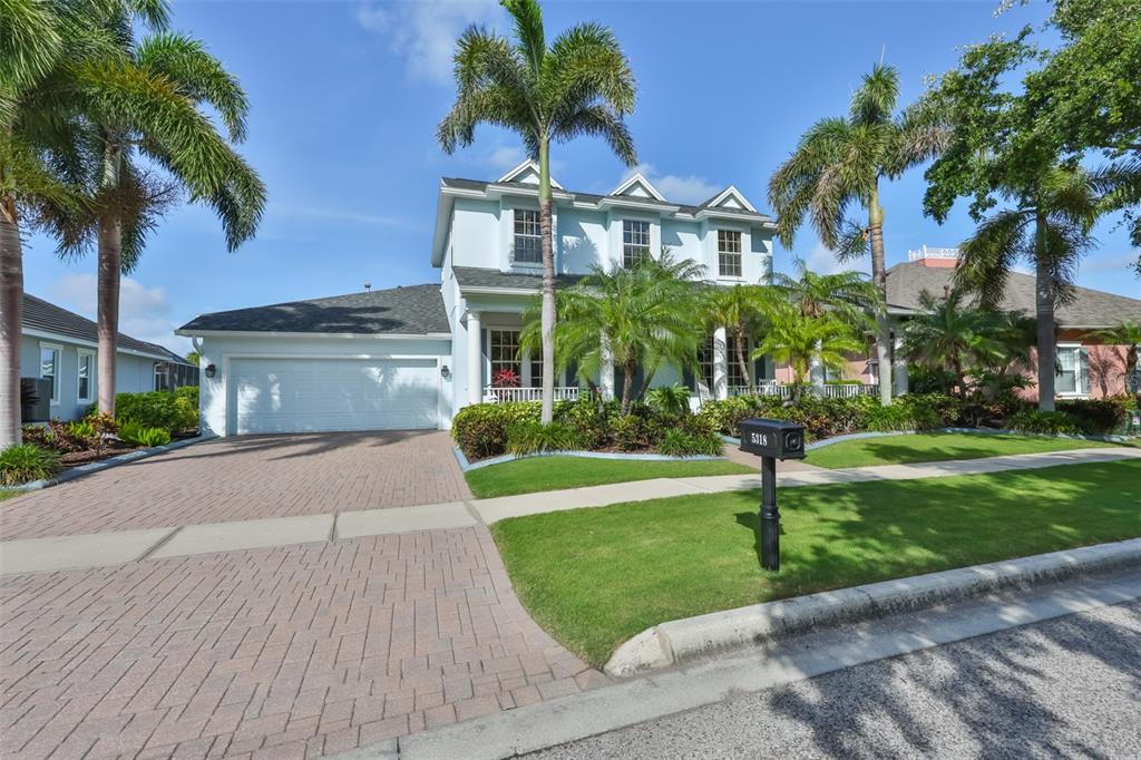 A two-story light blue house with a paved driveway, palm trees, and a front lawn — 5318 LOON NEST COURT, APOLLO BEACH, FL