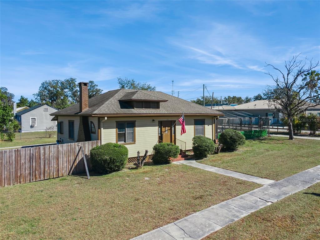 A single-story house with tan siding, a brown roof, and a chimney sits on a lawn — 116 W ARBORVITAE LANE, POLK CITY, FL