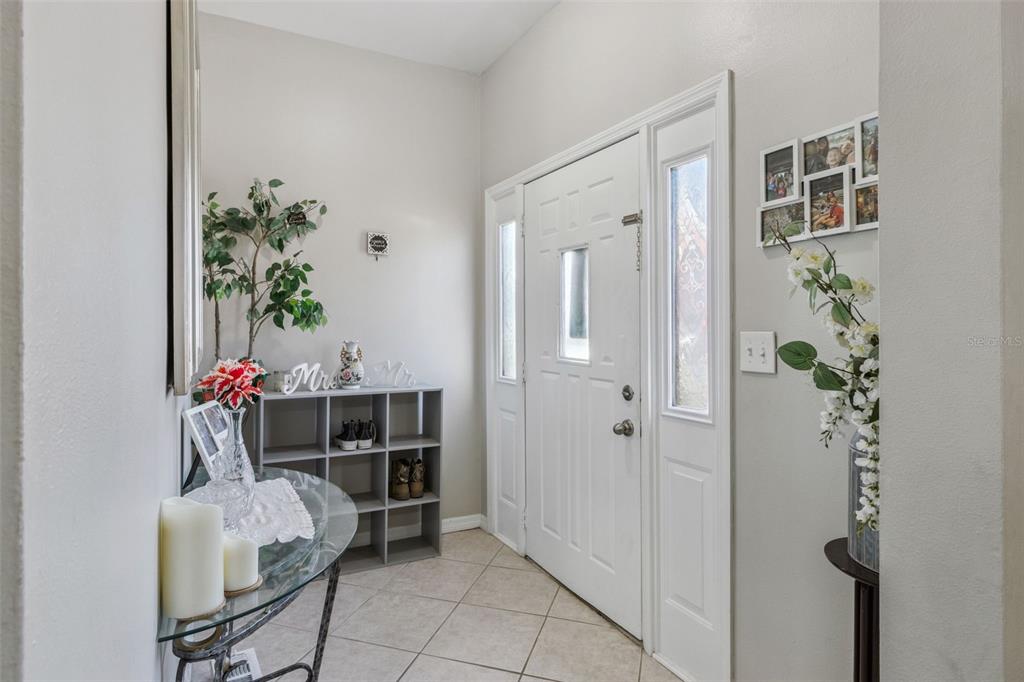 An entryway features a white front door, tiled flooring, a glass console table, and shelving — 116 W ARBORVITAE LANE, POLK CITY, FL