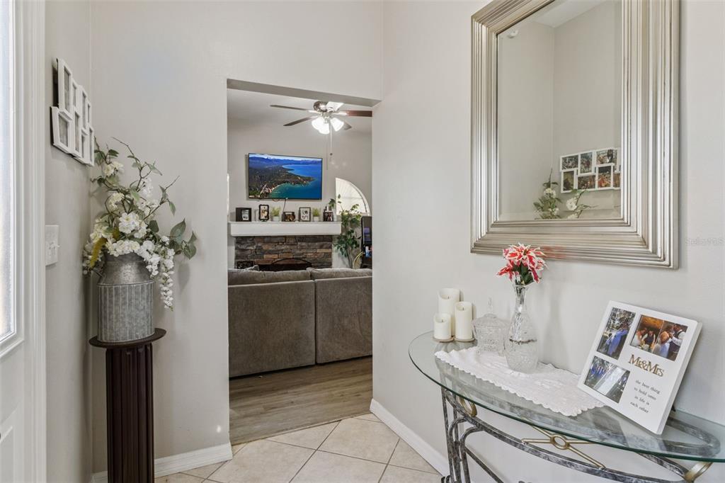A foyer features a glass console table, a large mirror, and a view into the living room — 116 W ARBORVITAE LANE, POLK CITY, FL