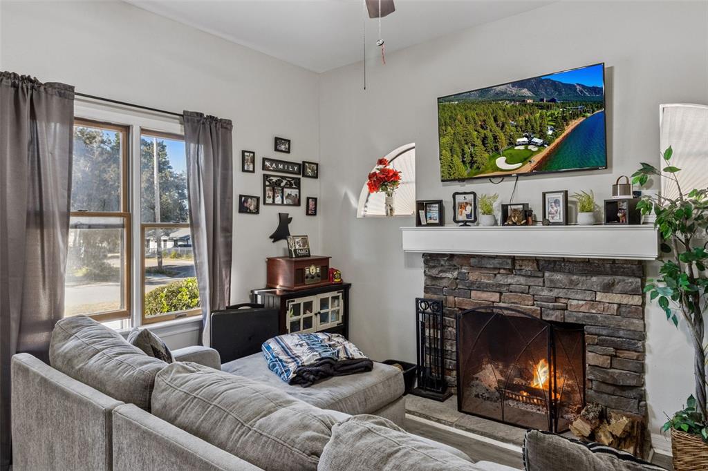 A living room features a stone fireplace, a wall-mounted television, and a gray sectional sofa — 116 W ARBORVITAE LANE, POLK CITY, FL