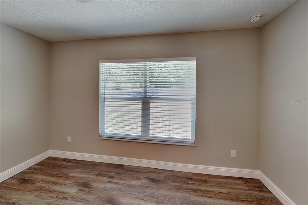 An empty room features light-colored walls, wood-look flooring, white baseboards, and a single window — 7961 N PRIMROSE DRIVE, CITRUS SPRINGS, FL