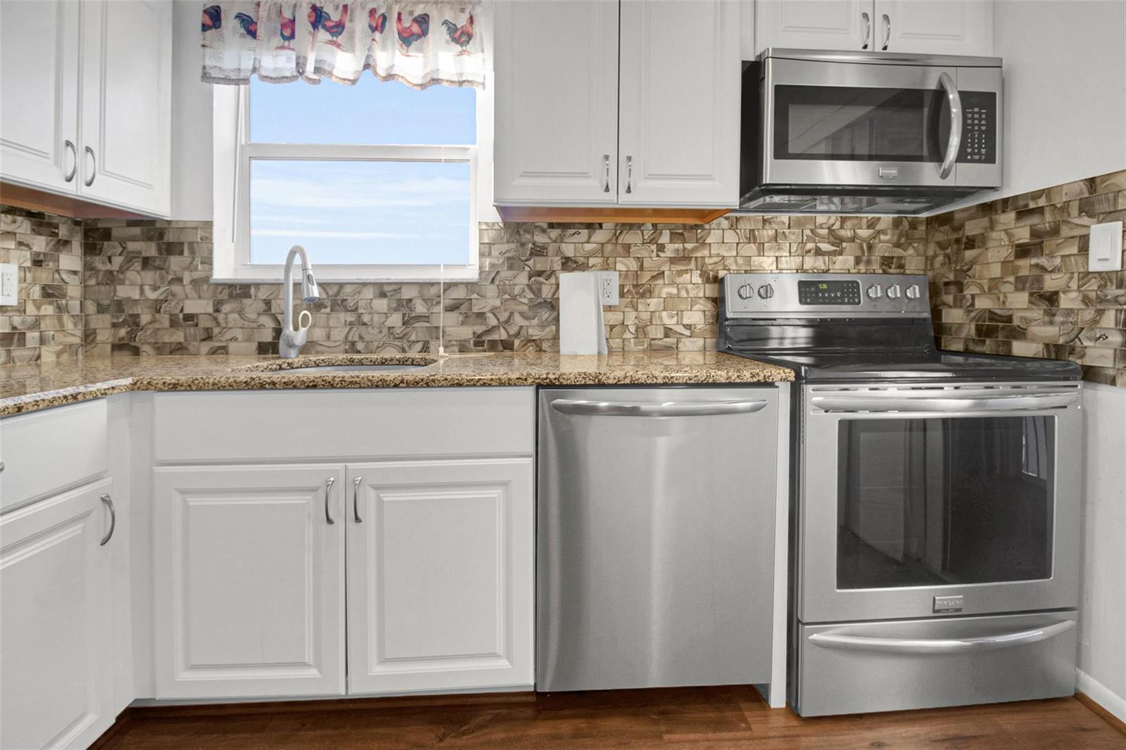 A kitchen features white cabinets, stainless steel appliances, granite countertops, and a decorative tile backsplash — 6890 Royal Palm Boulevard # 312h, Margate FL 33063, MARGATE, FL