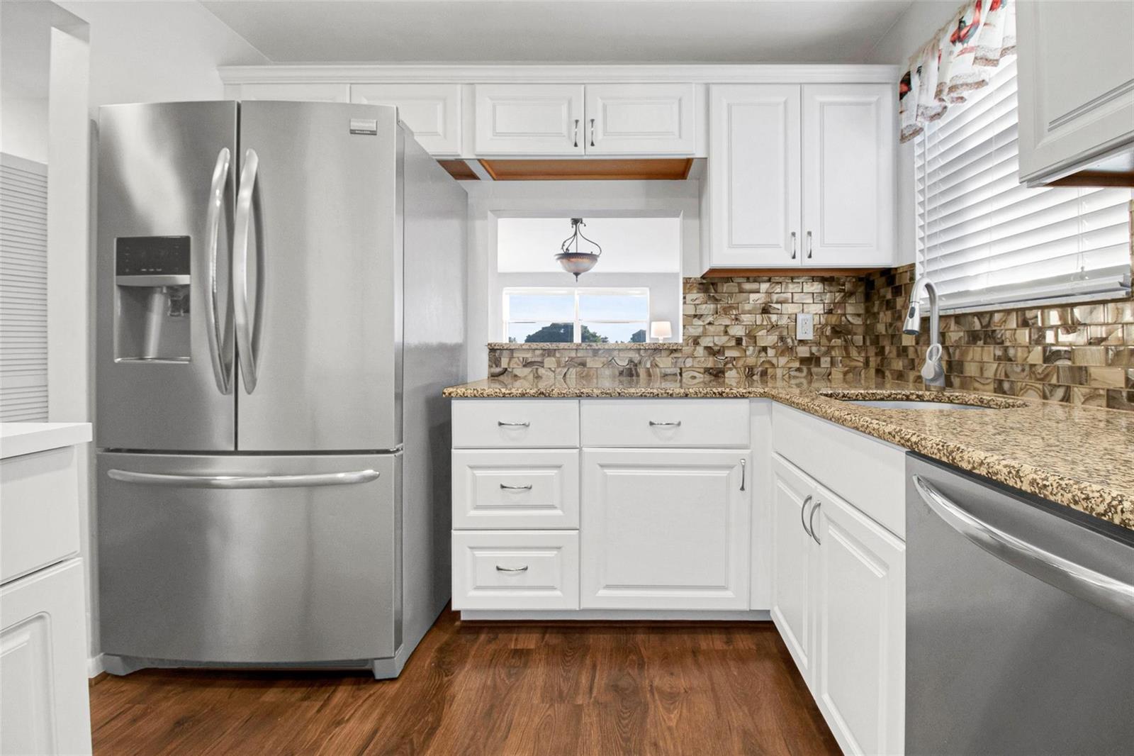 A kitchen features white cabinets, stainless steel appliances, granite countertops, and a brown tile backsplash — 6890 Royal Palm Boulevard # 312h, Margate FL 33063, MARGATE, FL