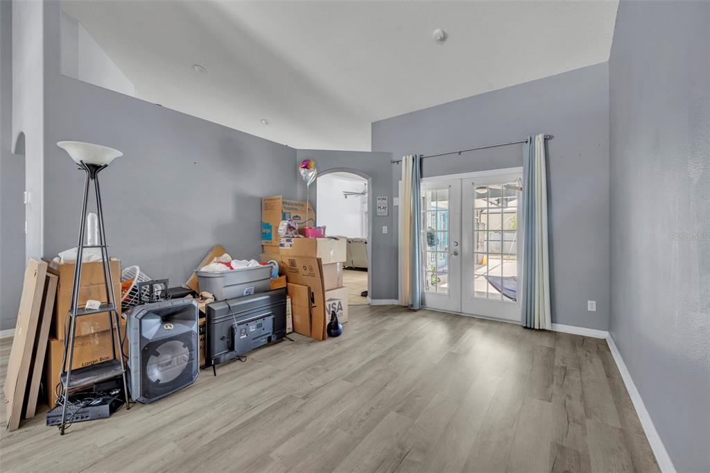 A living room with gray walls, wood-look flooring, and a stack of moving boxes — 15115 GREATER GROVES BOULEVARD, CLERMONT, FL