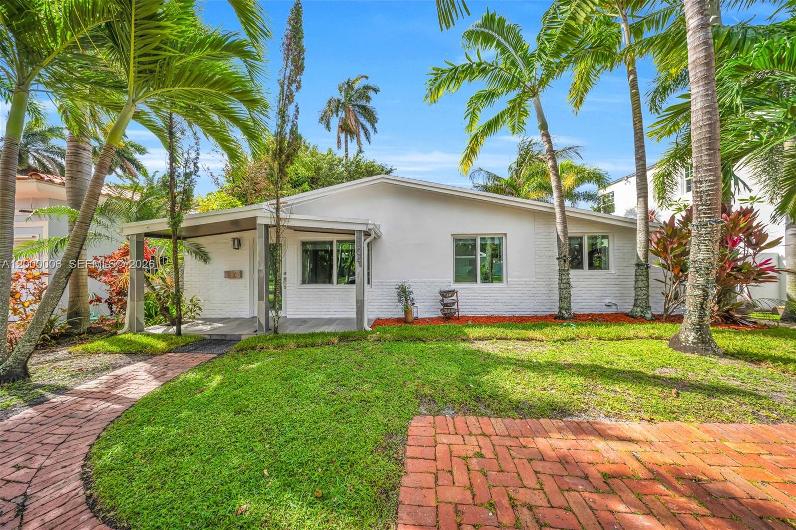 A white single-story house features a covered porch, brick walkway, and surrounding palm trees — 1104 NE 85th St, Miami FL 33138, MIAMI, FL