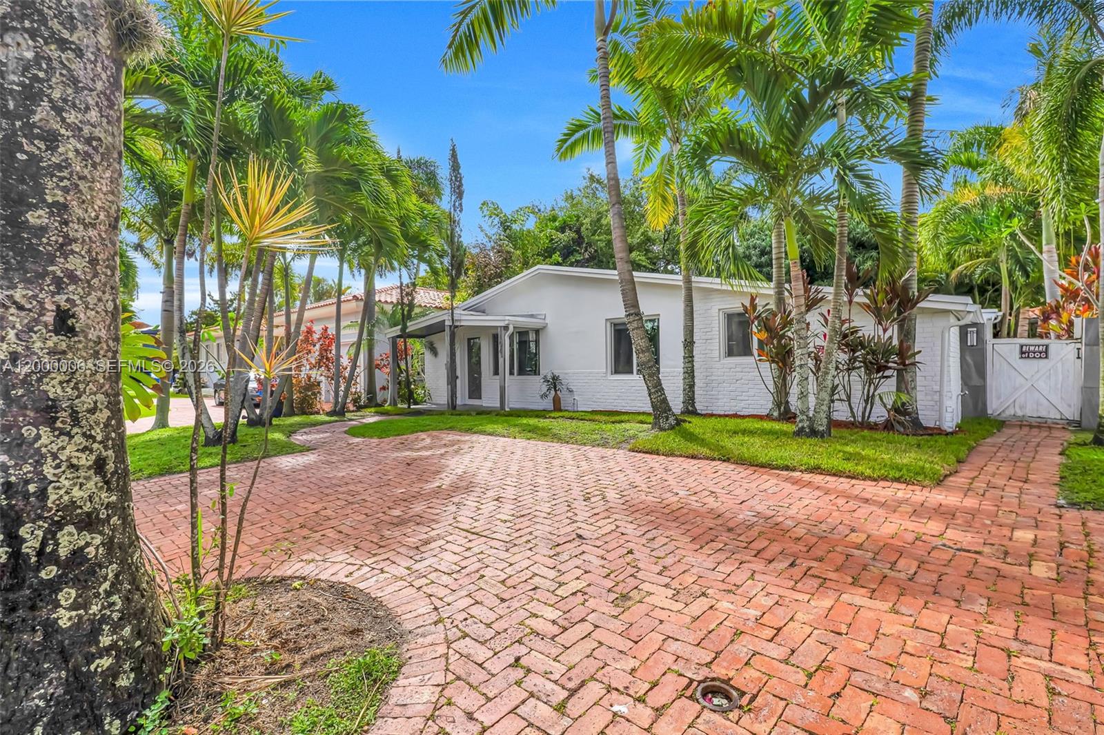 A white single-story house features a brick driveway and palm trees in the front yard — 1104 NE 85th St, Miami FL 33138, MIAMI, FL