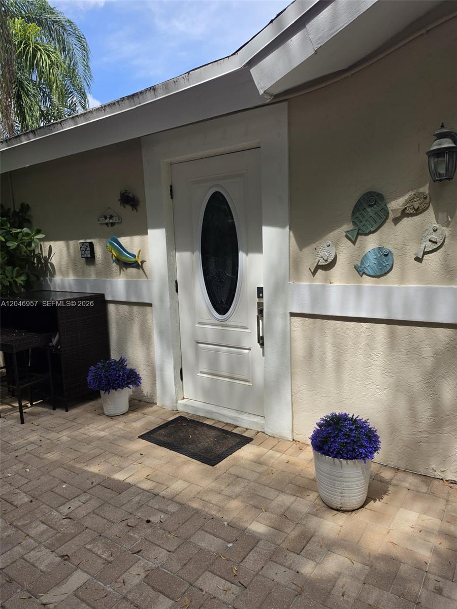 A white front door with an oval glass insert sits on a paved patio — 9760 SW 148th St, Miami FL 33176, MIAMI, FL