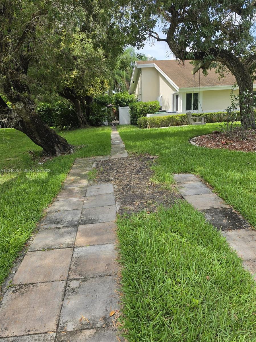 A paved walkway leads through a grassy yard toward a house with a tree swing — 9760 SW 148th St, Miami FL 33176, MIAMI, FL