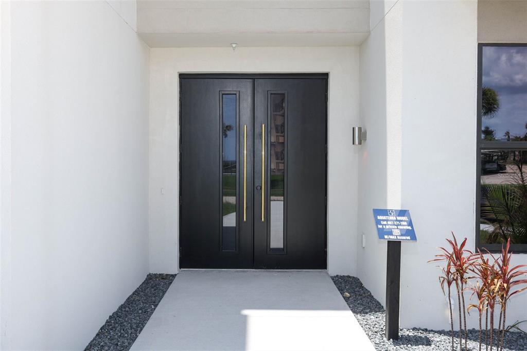 A modern black double front door with vertical glass panels and gold handles — 2360 OCEAN SHORE BOULEVARD UNIT 5, ORMOND BEACH, FL