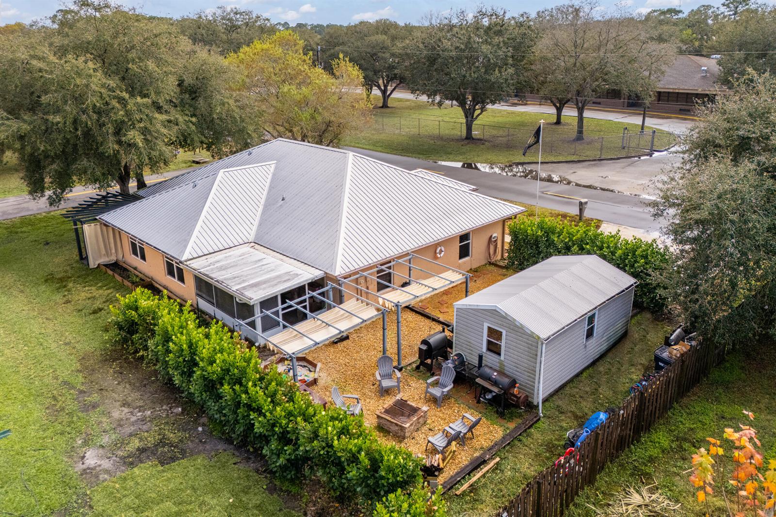 An aerial view of a house with a metal roof, a patio, and a detached shed — 3789 SE 6th Street, Okeechobee FL 34974, OKEECHOBEE, FL