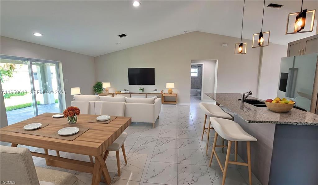 An open-concept living and dining area features white tile floors, a kitchen island, and furniture — 8038 Sunrise Cir., La Belle FL 33935, LA BELLE, FL