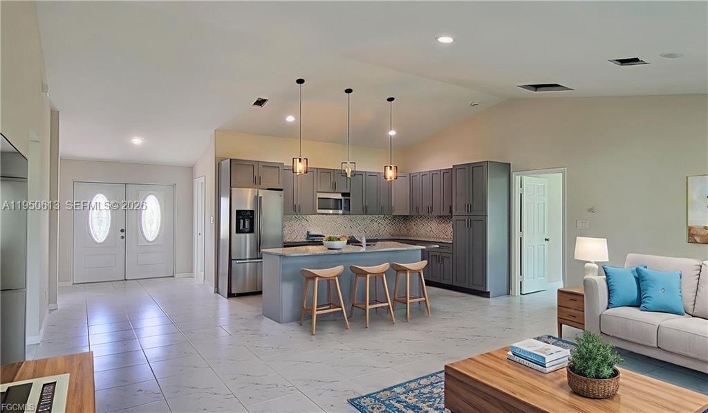 A kitchen with grey cabinets and a central island sits in an open-concept living space — 8038 Sunrise Cir., La Belle FL 33935, LA BELLE, FL