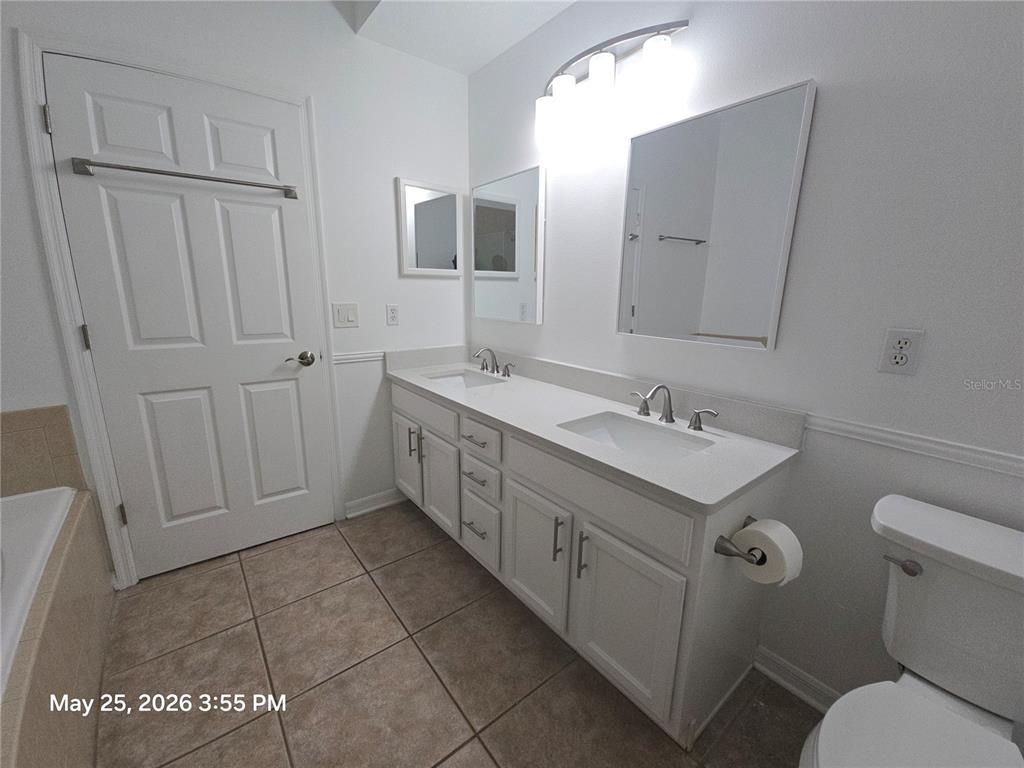 A bathroom features a double vanity with white cabinets, a quartz countertop, and two mirrors — 14751 SEATTLE SLEW PLACE, ORLANDO, FL