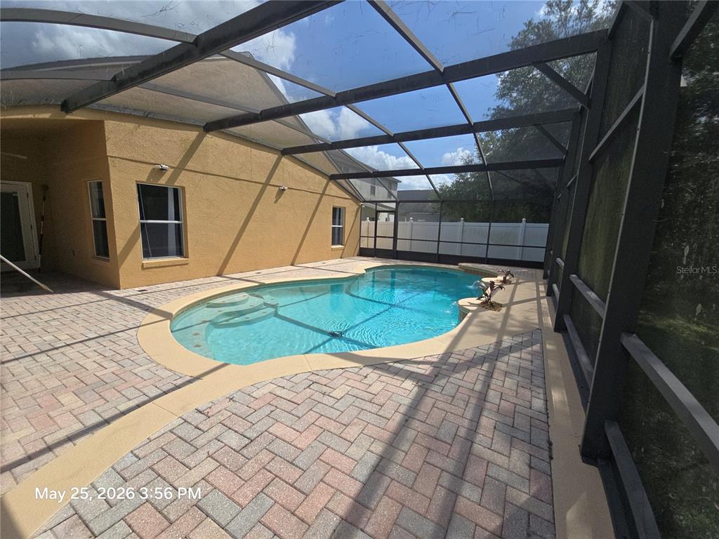 A screened-in patio features a kidney-shaped swimming pool surrounded by brick pavers — 14751 SEATTLE SLEW PLACE, ORLANDO, FL