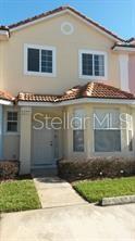 A two-story residential building with a tan stucco exterior, a tiled roof, and a front entrance — 1209 S BEACH CIRCLE, KISSIMMEE, FL