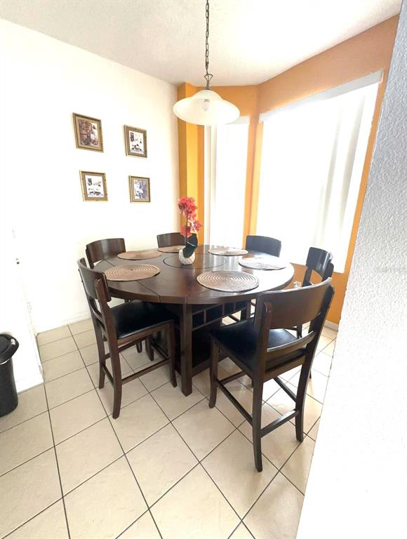A dining area features a round wooden table with six chairs and tile flooring — 1209 S BEACH CIRCLE, KISSIMMEE, FL