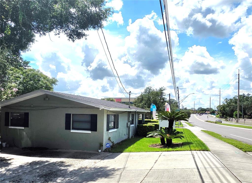 A single-story building with gray stucco siding sits next to a road and sidewalk — 498 ESTHER LANE, ALTAMONTE SPRINGS, FL