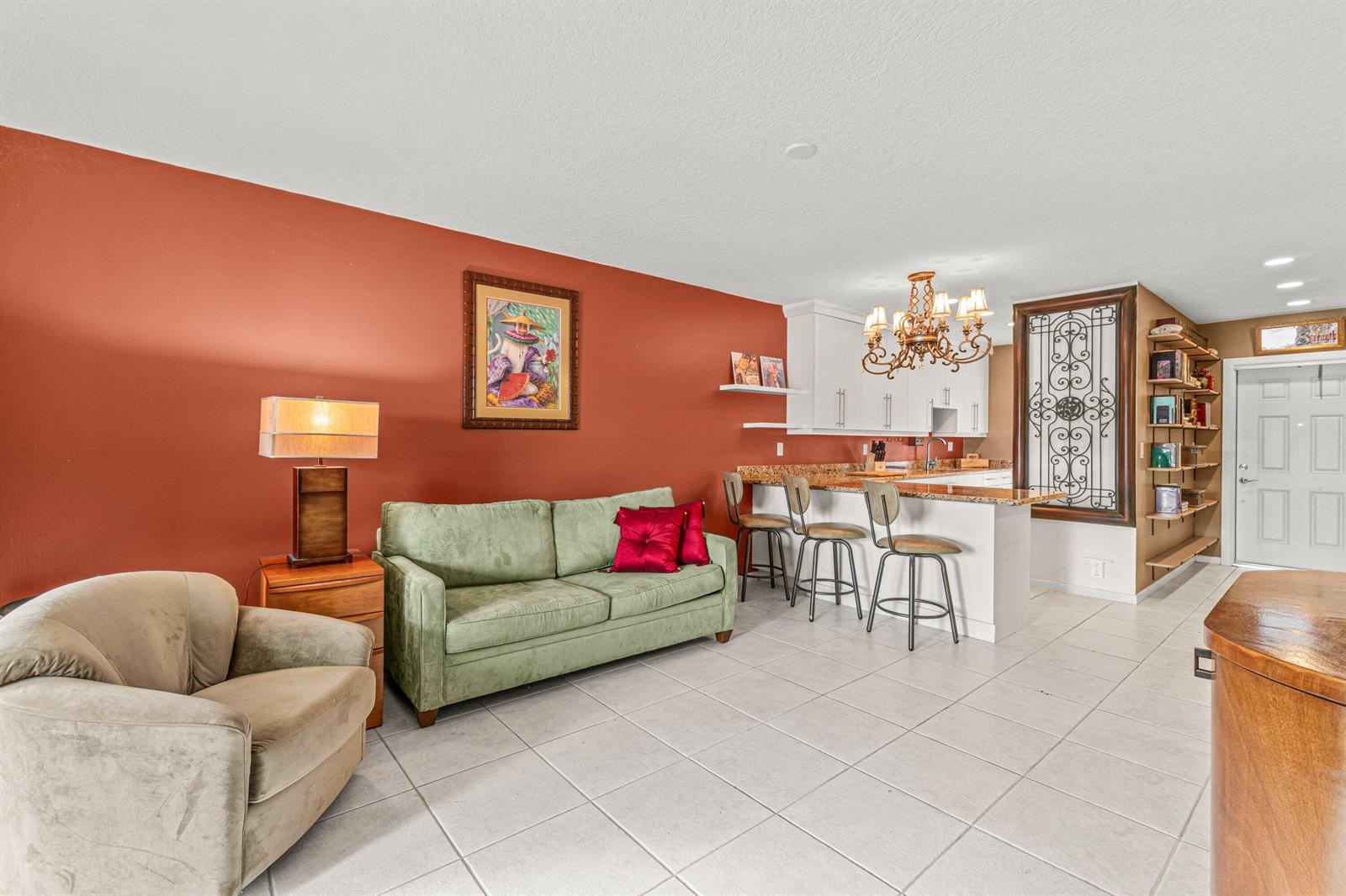 A living room with a green sofa, an armchair, and an open kitchen with bar seating — 1118 Lake Terrace # H, Boynton Beach FL 33426, BOYNTON BEACH, FL