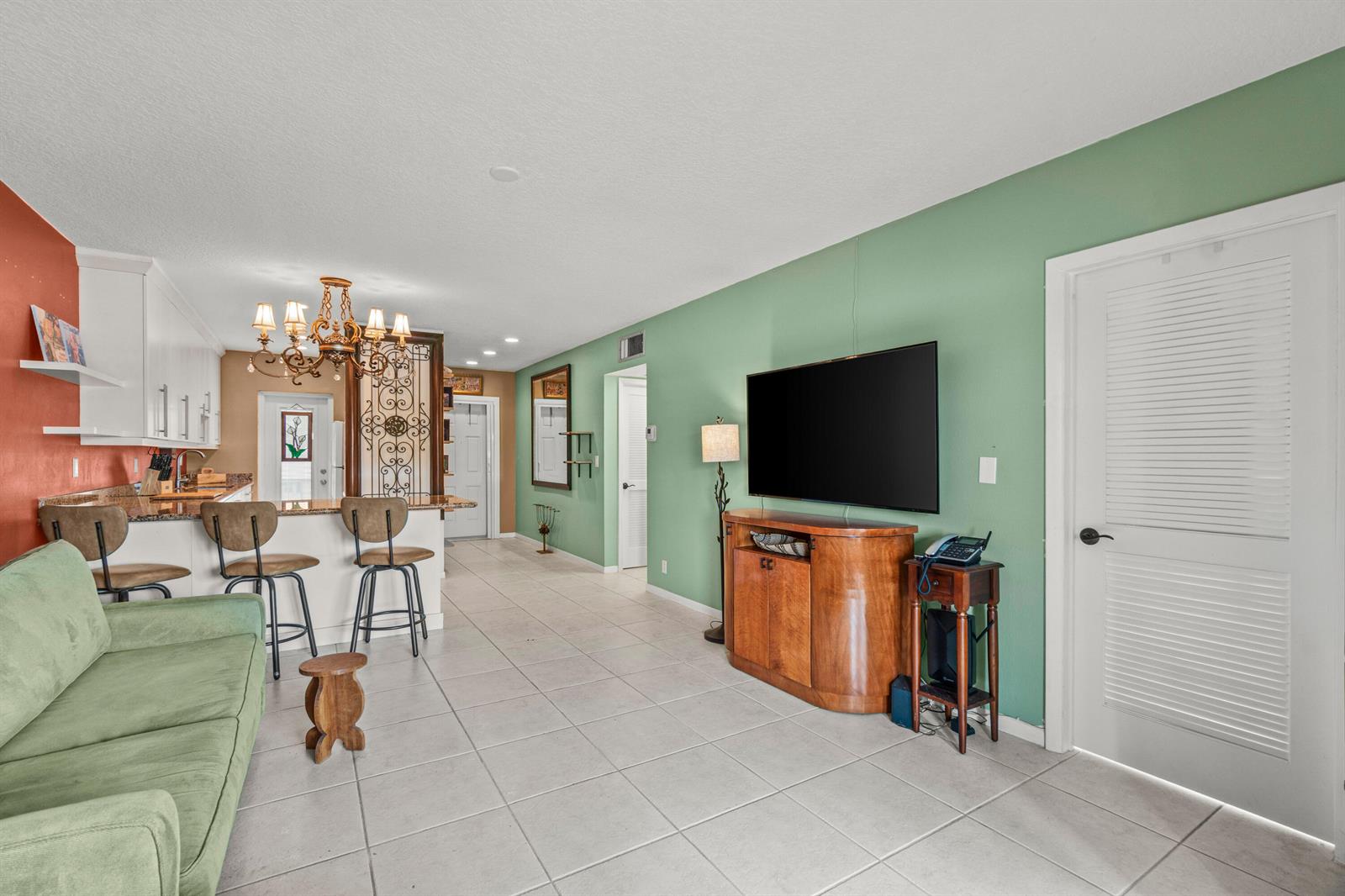 A living room with a green wall, a wall-mounted television, and an adjacent kitchen area — 1118 Lake Terrace # H, Boynton Beach FL 33426, BOYNTON BEACH, FL