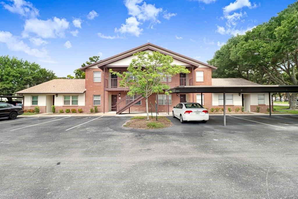A two-story brick apartment building with a parking lot and covered parking spaces — 2440 ENTERPRISE ROAD UNIT 2, CLEARWATER, FL
