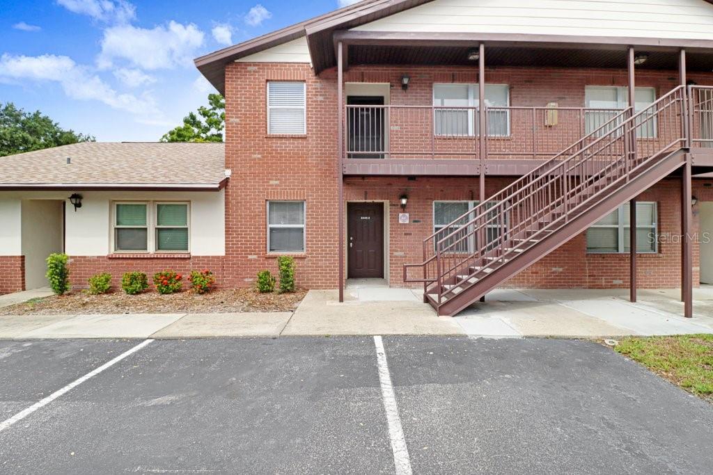 A two-story brick apartment building features an exterior staircase and a paved parking lot — 2440 ENTERPRISE ROAD UNIT 2, CLEARWATER, FL