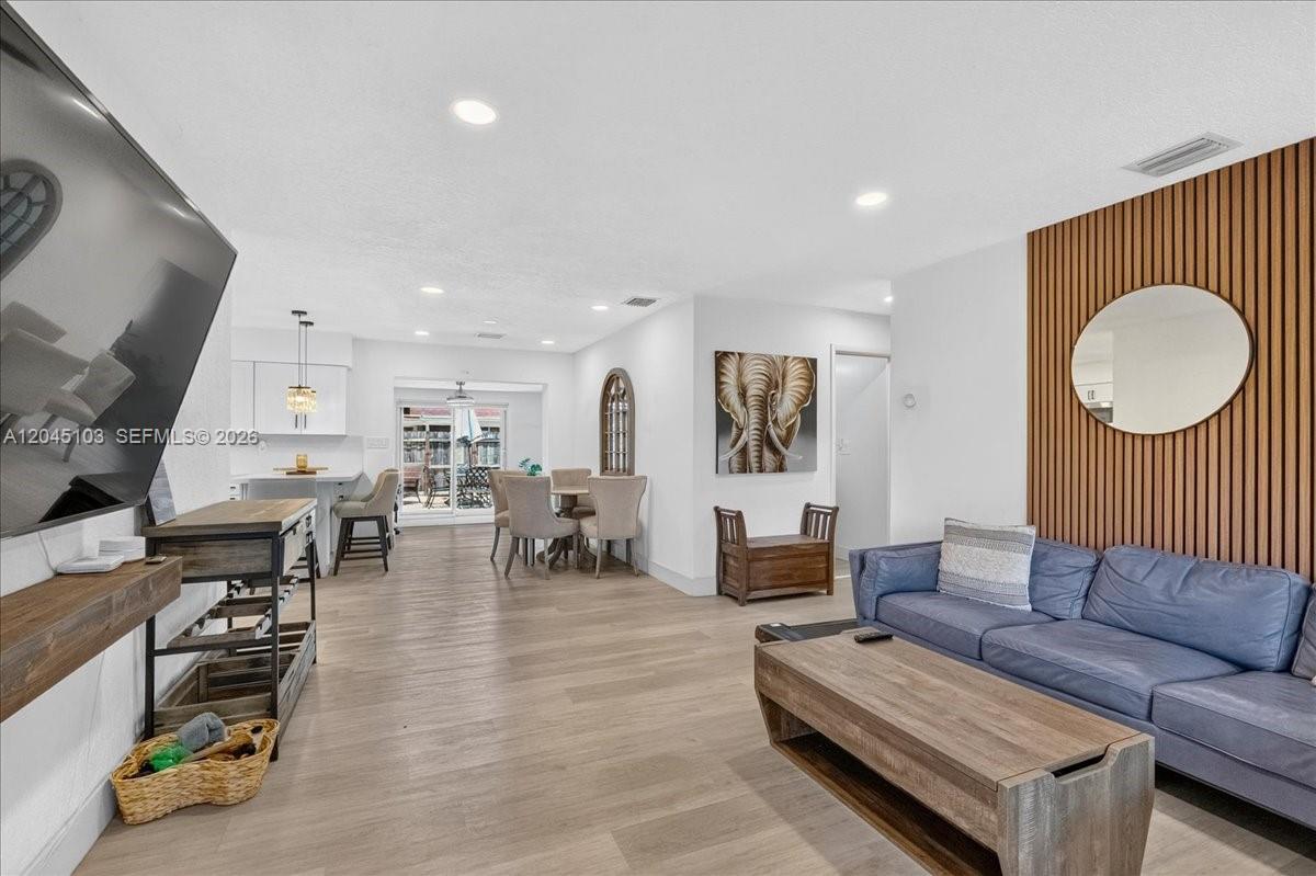 A living room with wood-slat wall paneling, a blue sofa, and an adjacent dining area — 1131 N 75th Ave, Hollywood FL 33024, HOLLYWOOD, FL