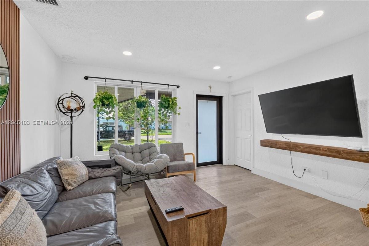 A living room features a leather sofa, a wooden coffee table, and a wall-mounted television — 1131 N 75th Ave, Hollywood FL 33024, HOLLYWOOD, FL