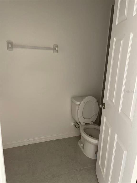 A small bathroom features a white toilet and a towel bar on a gray wall — 34224 ROGALLO LANE, WESLEY CHAPEL, FL