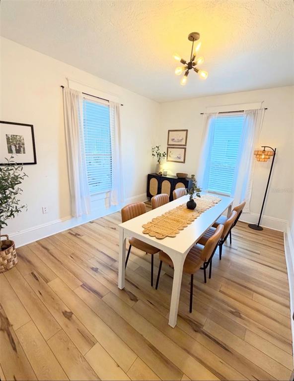A bright entryway features light wood flooring, a white staircase, and a view into a kitchen — 402 E POINSETTIA STREET, LAKELAND, FL