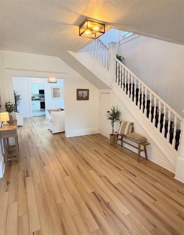 A bright entryway features white walls, wood-look flooring, a staircase, and a front door — 402 E POINSETTIA STREET, LAKELAND, FL
